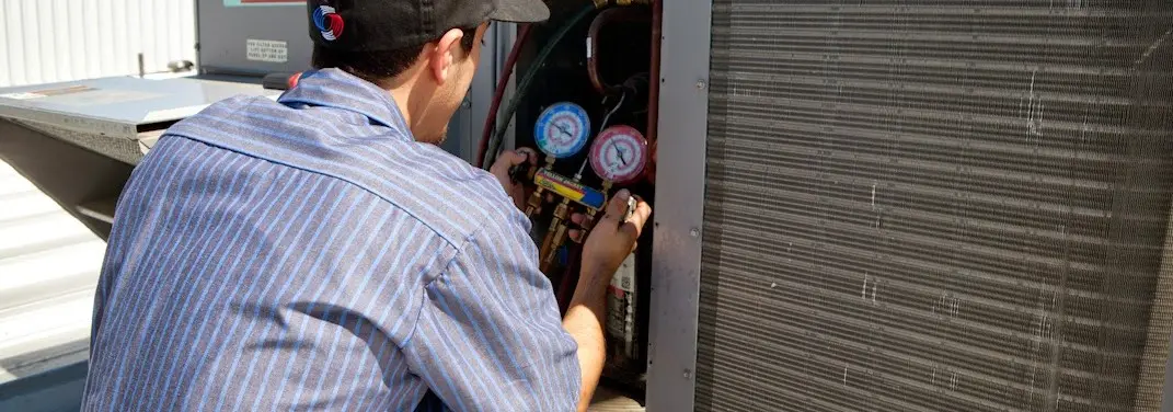 HVAC technician servicing a condenser unit in Fairlawn